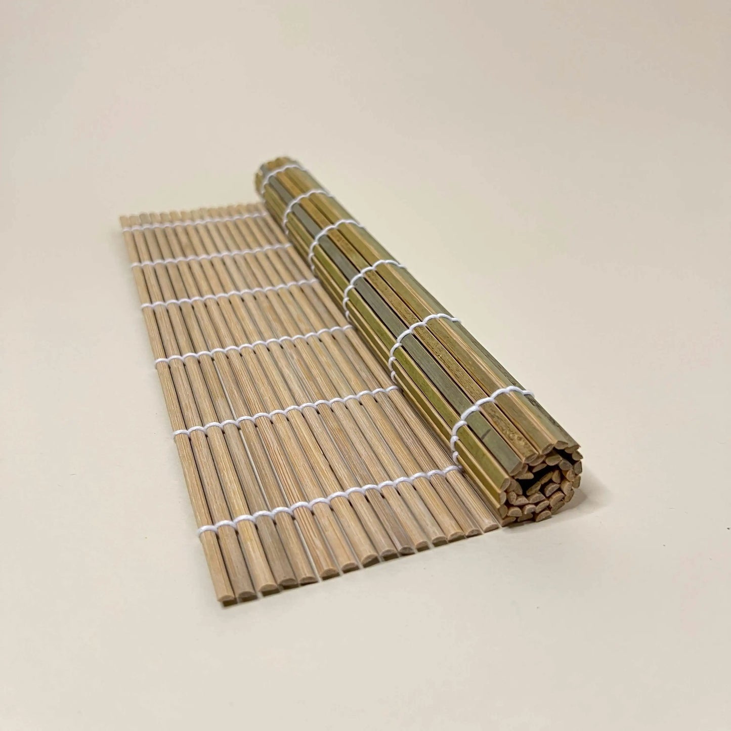 Roll of a sushi bamboo mat 27cm x27cm on a beige background