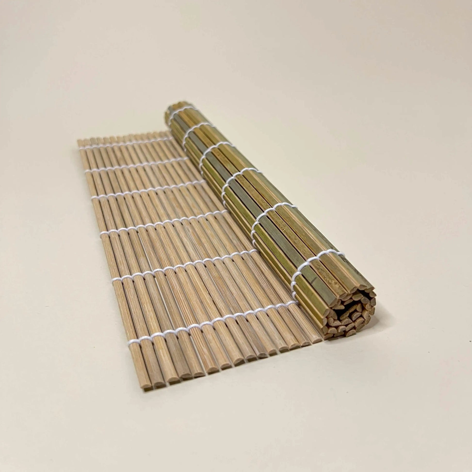 Roll of a sushi bamboo mat 27cm x27cm on a beige background