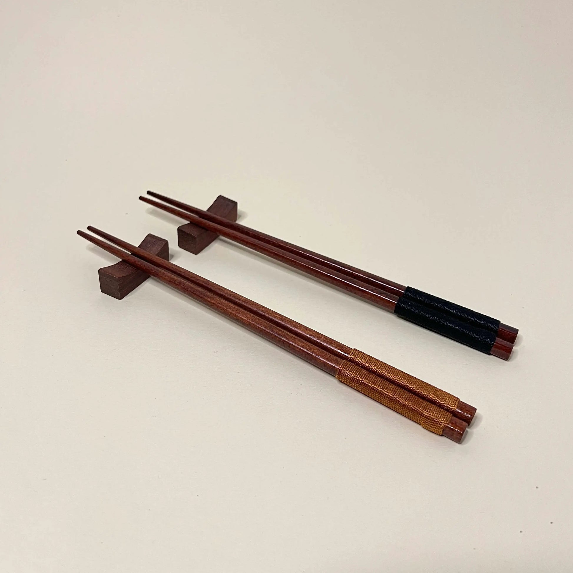 Set of wooden chopsticks with black accents on a beige background